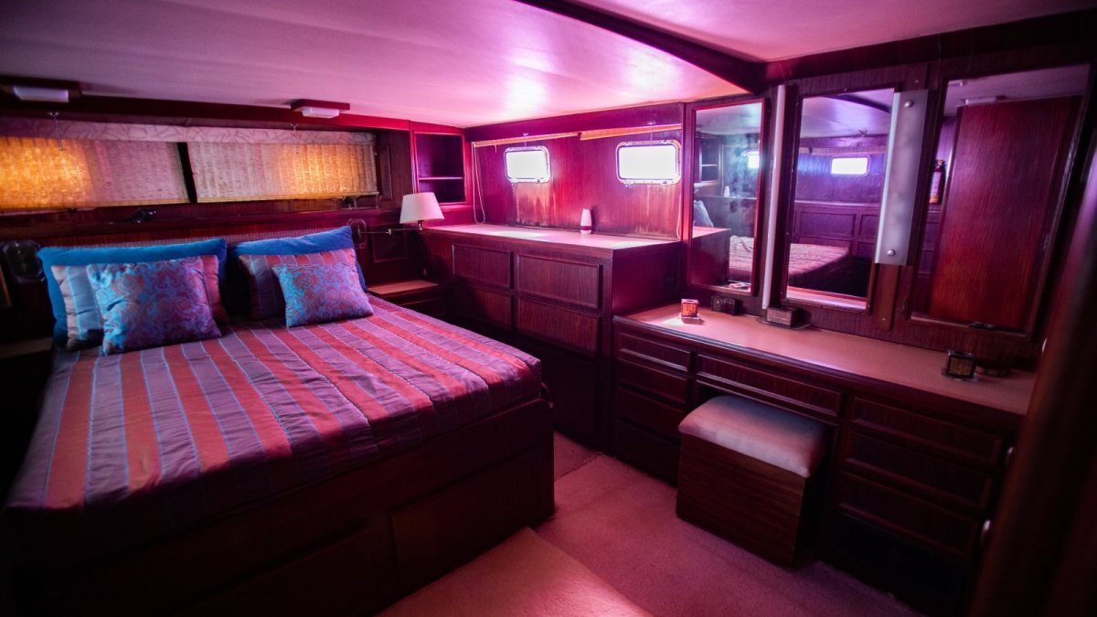 Camarote principal de un yate clásico en Puerto Vallarta con cama sobre cajones, carpintería de madera y espejos en puertas de clóset